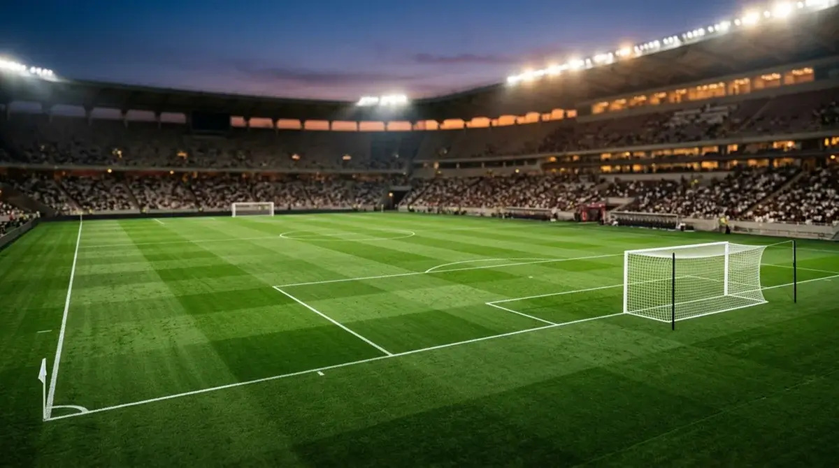 A soccer pitch under stadium lights with empty stands at dusk before kickoff
